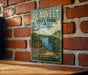 A vintage metal sign for Blauvelt State Park in New York, featuring a scenic image of the Hudson Valley and a sign indicating the park's nature, recreation, and history.