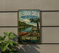 A vintage-style metal sign for Tennessee State Park, featuring a scenic image of a lake and canoe, mounted on a wall.