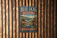 A vintage metal sign for Blue Licks Battlefield State Resort Park in Kentucky, featuring a historical illustration of soldiers and a scenic landscape.