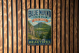 A vintage metal sign for Blue Mound State Park in Wisconsin, featuring a scenic mountain landscape.