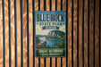 A vintage-style metal sign for Blue Rock State Park in Ohio, featuring a scenic landscape with a lake and mountains.