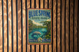 A vintage-style metal sign for Blue Spring State Park in Florida, featuring a scenic illustration of a manatee in a body of water surrounded by palm trees.
