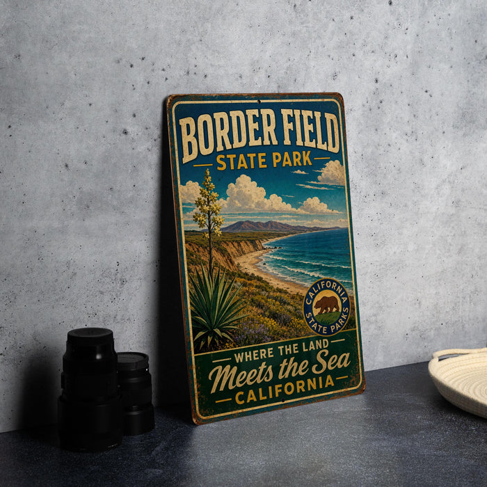 A vintage-style metal sign for Border Field State Park, featuring a scenic landscape with mountains, a beach, and a palm tree.