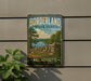 A vintage metal sign for Borderland State Park in Massachusetts, featuring a scenic landscape with a lake, trees, and a stone wall.