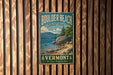 A vintage metal sign for Boulder Beach State Park in Vermont, featuring a scenic landscape with mountains, a lake, and a rocky shoreline.