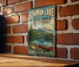A vintage-style metal sign for Bowman Lake State Park in New York, featuring a scenic image of a lake with a red canoe and a mountain backdrop.