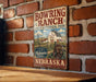 A vintage-style metal sign for Bowring Ranch Historical Park in Nebraska, featuring a barn, windmill, and other rural elements.