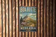 A vintage metal sign for Box Butte State Recreation Area in Nebraska, featuring a mountain landscape and a road leading to the mountain.