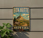 A vintage-style metal sign for Box Butte State Recreation Area in Nebraska, featuring a mountain landscape and a road leading to the entrance.
