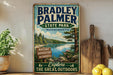 A vintage-style metal sign for Bradley Palmer State Park in Massachusetts, featuring a scenic landscape with a lake and pine trees.