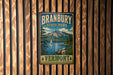 A vintage metal sign for Branbury State Park in Vermont, featuring a scenic landscape with a lake, mountains, and a sailboat.