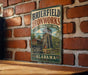 A vintage metal sign for Brierfield Ironworks, a historical state park in Alabama, is displayed on a brick wall.