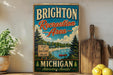 A vintage-style metal sign for Brighton Recreation Area in Michigan, featuring a scenic landscape with a lake, pine trees, and a red canoe.
