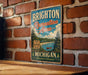 A vintage metal sign for Brighton Recreation Area in Michigan, featuring a scenic image of a lake and forest.