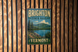 A vintage metal sign for Brighton State Park in Vermont, featuring a scenic landscape with mountains, trees, and a lake.