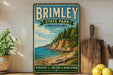 A vintage-style metal sign for Brimley State Park in Michigan, featuring a scenic coastal landscape with a rocky cliff, pine trees, and a beach.