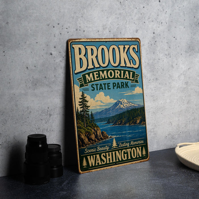 A vintage-style sign for Brooks Memorial State Park in Washington, featuring a scenic landscape with a mountain, lake, and pine trees.