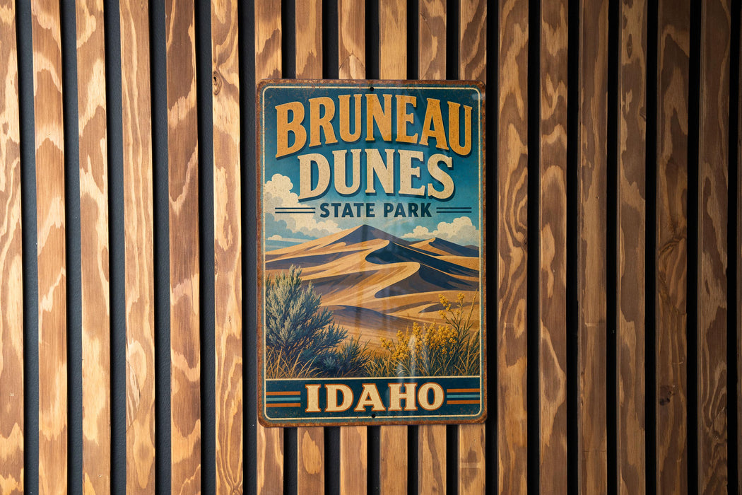 A vintage metal sign for Brunette Dunes State Park in Idaho, featuring a desert landscape with sand dunes and mountains in the background.