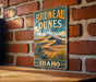 A vintage-style metal sign for Brunette Dunes State Park in Idaho, featuring a desert landscape with mountains and desert vegetation.