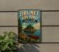 A vintage-style metal sign for Brunet Island State Park in Wisconsin, featuring a scenic image of a lake, pine trees, and a canoe.