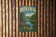 A vintage-style metal sign for Buck Creek State Park in Ohio, featuring a scenic image of the park and its surroundings.