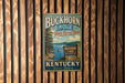 A vintage metal sign for Buckhorn Lake State Resort Park in Kentucky, featuring a scenic illustration of the lake surrounded by trees and mountains.