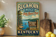 A vintage-style metal sign for Buckhorn Lake State Resort Park in Kentucky, featuring a scenic illustration of the lake surrounded by pine trees and mountains.