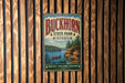 A vintage metal sign for Buckhorn State Park in Wisconsin, featuring a scenic landscape with a lake, mountains, and a red canoe.