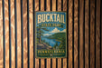 A vintage metal sign for Bucktail State Park in Pennsylvania, featuring a scenic landscape with a lake and mountains.