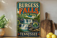 A vintage-style sign forBURGESS FALLS State Park in Tennessee, featuring a waterfall and lush greenery, is displayed on a shelf next to a wooden cutting board and some lemons.