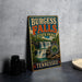 A vintage-style sign forBURGESS FALLS State Park in Tennessee, featuring a waterfall and lush greenery, is displayed on a gray countertop next to a stack of black camera lenses.