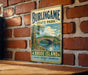 A vintage metal sign for Burlingame State Park, Rhode Island, featuring a scenic landscape with a bridge and trees.