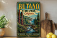 A vintage-style metal sign for Butano State Park, California, featuring a scenic landscape with a river, mountains, and forests.
