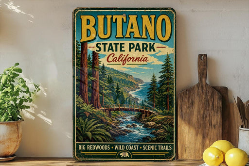 A vintage-style metal sign for Butano State Park, California, featuring a scenic landscape with a river, mountains, and forests.
