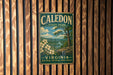 A vintage metal sign for Caledon State Park in Virginia, featuring a scenic landscape with a river, trees, and flowers.