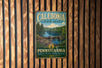 A vintage metal sign for Caledonia State Park in Pennsylvania, featuring a scenic landscape with a river, bridge, and trees.