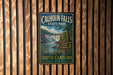 A vintage metal sign for Calhoun Falls State Park, featuring a waterfall and lush greenery, is displayed on a wooden wall.