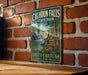 A vintage metal sign for Calhoun Falls State Park, featuring a scenic illustration of a waterfall and lush greenery, is displayed on a brick wall.