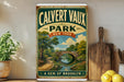 A vintage-style poster of Calvert Vaux Park in New York, featuring a scenic landscape with a bridge and trees, is displayed on a wall next to a wooden cutting board and some kitchen utensils.