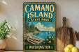A vintage-style sign for Camano Island State Park in Washington, featuring a scenic landscape with a lake, pine trees, and a sailboat.