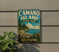 A vintage-style metal sign for Camano Island State Park in Washington, featuring a scenic landscape with a beach, mountains, and a sailboat.