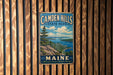 A vintage metal sign for Camden Hills State Park in Maine, featuring a scenic landscape with mountains, ocean, and a pine tree.