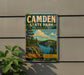 A vintage metal sign for Camden State Park in Minnesota, featuring a scenic landscape with pine trees, a lake, and mountains.