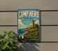 a vintage-style metal sign for Camp Hero State Park in New York, with a lighthouse and a coastal landscape in the background.