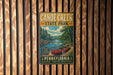 A vintage-style metal sign for Canoe Creek State Park in Pennsylvania, featuring a scenic image of a canoe on a river surrounded by trees.