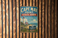 A vintage metal sign for Cape May Point State Park in New Jersey, featuring a lighthouse and a beach scene.