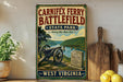 a vintage-style sign for Carniffex Ferry Battlefield State Park, with a cannon and a gravestone in the foreground, and a wooden cutting board and a potted plant to the side.