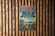 A vintage metal sign for Carolina Beach State Park, featuring a scenic beach and pier view, is displayed on a wooden wall.