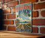 A vintage metal sign for Carolina Beach State Park, featuring a scenic beach view with a wooden pier and a sign indicating the park's nature, recreation, and adventure offerings.
