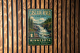A vintage-style metal sign for Cascade River State Park in Minnesota, featuring a scenic image of the waterfall and forest.